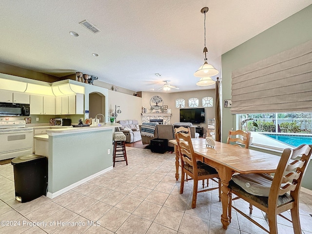 dining area featuring ceiling fan, a textured ceiling, light tile patterned floors, and sink