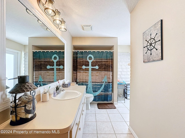 bathroom featuring toilet, vanity, a textured ceiling, and tile patterned floors