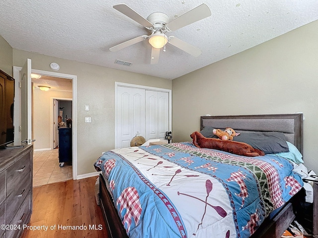 bedroom featuring a closet, a textured ceiling, hardwood / wood-style flooring, and ceiling fan