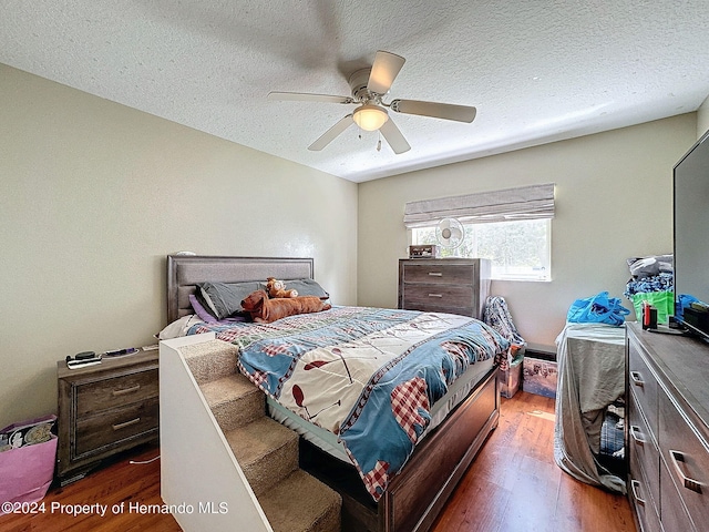 bedroom with a textured ceiling, ceiling fan, and dark hardwood / wood-style floors