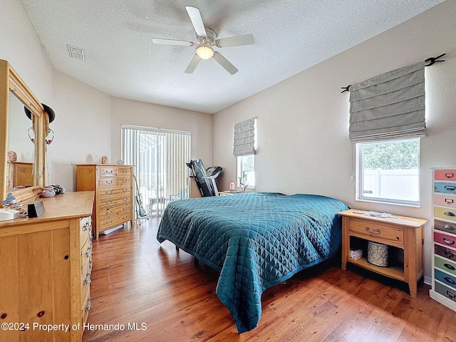 bedroom with a textured ceiling, hardwood / wood-style flooring, and ceiling fan