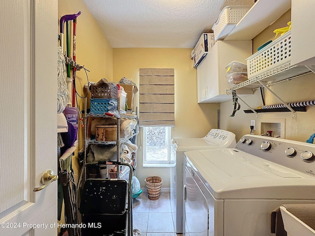 laundry room with tile patterned flooring, cabinets, a textured ceiling, and washer and dryer