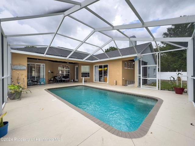 view of swimming pool featuring glass enclosure and a patio