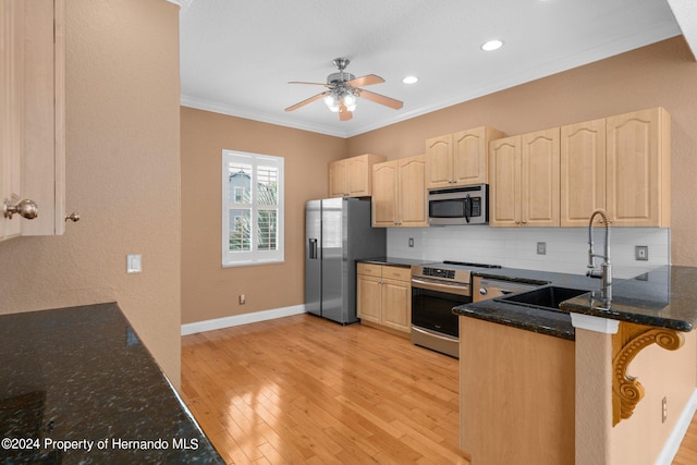 kitchen featuring kitchen peninsula, light hardwood / wood-style flooring, sink, crown molding, and appliances with stainless steel finishes