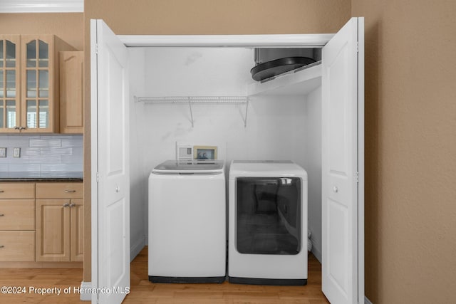 clothes washing area with light hardwood / wood-style floors and independent washer and dryer