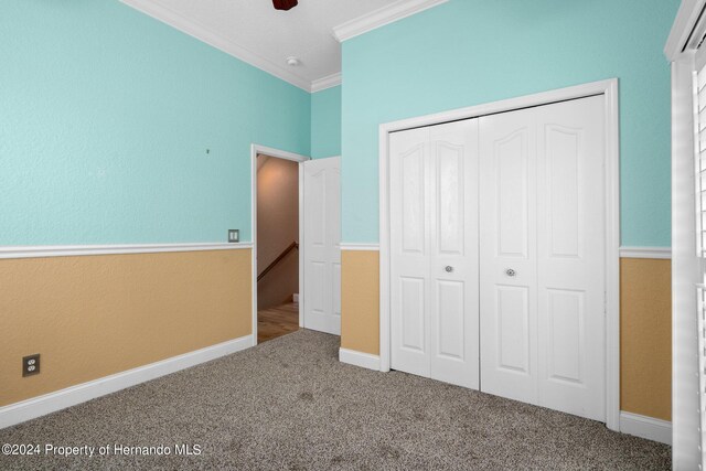 unfurnished bedroom with ornamental molding, carpet flooring, ceiling fan, and a closet