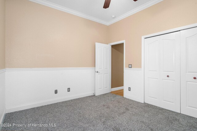 unfurnished bedroom with a closet, ceiling fan, carpet, and ornamental molding