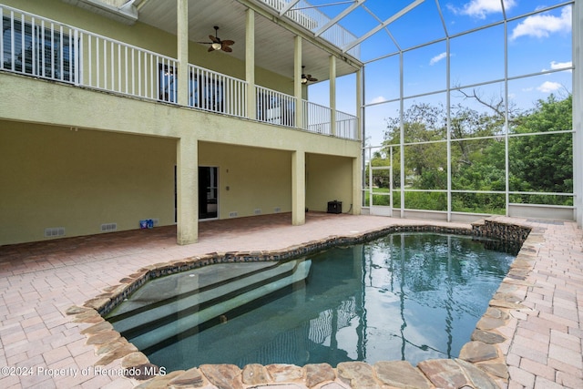 view of pool with glass enclosure, ceiling fan, and a patio area