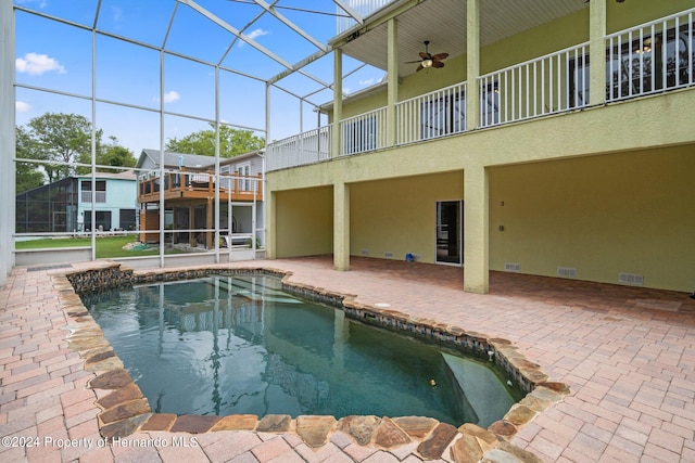 view of swimming pool featuring a patio, glass enclosure, and ceiling fan