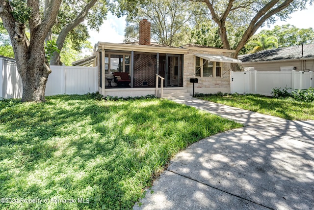 rear view of house with a lawn and a sunroom