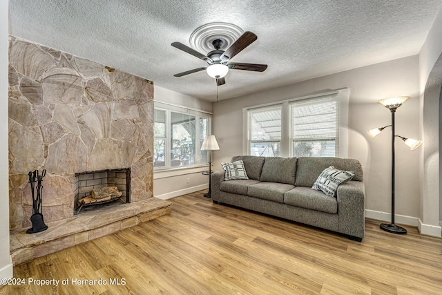 6635 Stewart Ave N, Saint Petersburg, FL 33702 - living area featuring baseboards, a textured ceiling, wood finished floors, a ceiling fan, and a fireplace