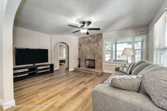 6635 Stewart Ave N, Saint Petersburg, FL 33702 - living room featuring arched walkways, ceiling fan, light wood-style flooring, a textured ceiling, and baseboards