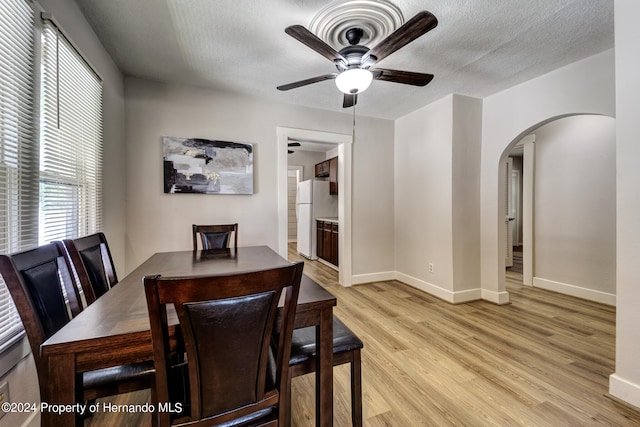 dining area with a textured ceiling, ceiling fan, and light hardwood / wood-style flooring