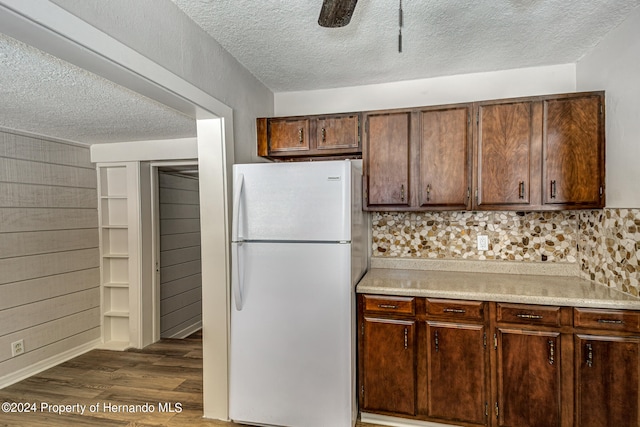 kitchen featuring white refrigerator, decorative backsplash, dark hardwood / wood-style floors, and a textured ceiling