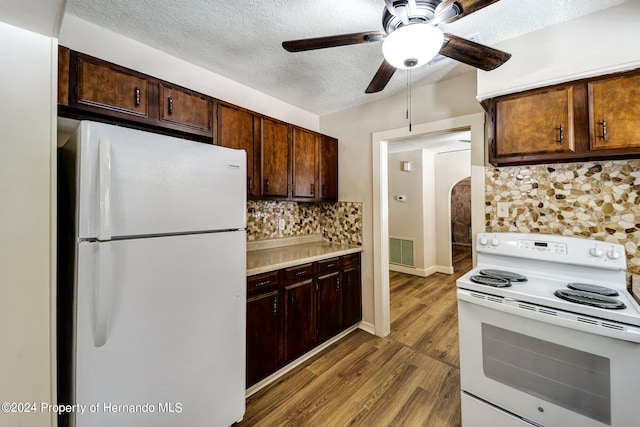 kitchen featuring dark brown cabinetry, white appliances, wood-type flooring, and tasteful backsplash