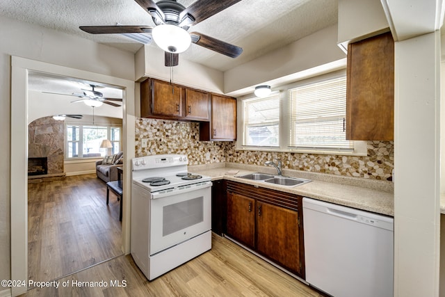 kitchen with sink, a textured ceiling, backsplash, white appliances, and light wood-type flooring