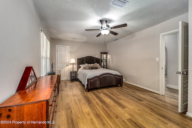 bedroom featuring wood-type flooring, ceiling fan, and a textured ceiling