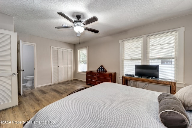 bedroom featuring a closet, ensuite bath, light wood-type flooring, a textured ceiling, and ceiling fan