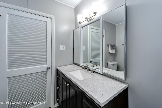 bathroom featuring vanity, toilet, and crown molding