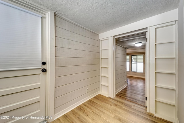 6635 Stewart Ave N, Saint Petersburg, FL 33702 - corridor with a textured ceiling, light wood-style floors, and wooden walls