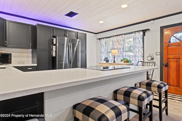 kitchen with black appliances, wooden ceiling, ornamental molding, a kitchen breakfast bar, and light wood-type flooring