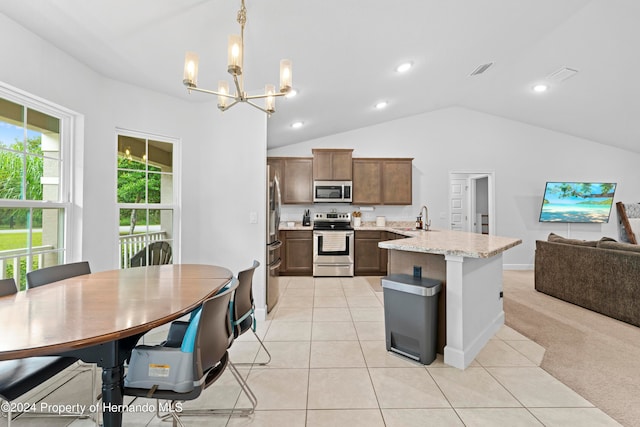 kitchen featuring stainless steel appliances, light tile patterned floors, pendant lighting, light stone countertops, and vaulted ceiling