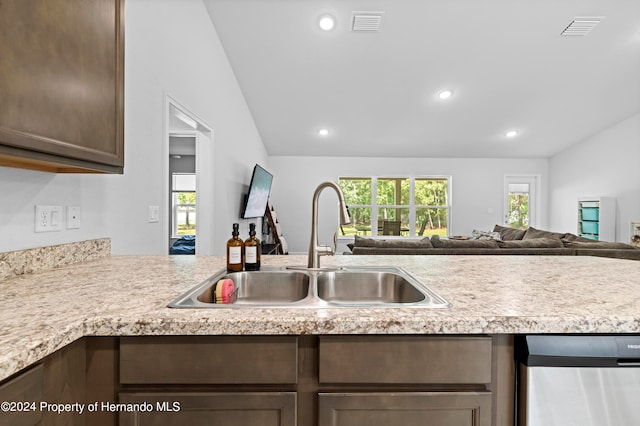 kitchen with sink, kitchen peninsula, stainless steel dishwasher, dark brown cabinets, and vaulted ceiling