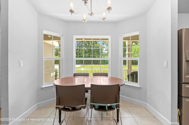 tiled dining space featuring a healthy amount of sunlight and an inviting chandelier