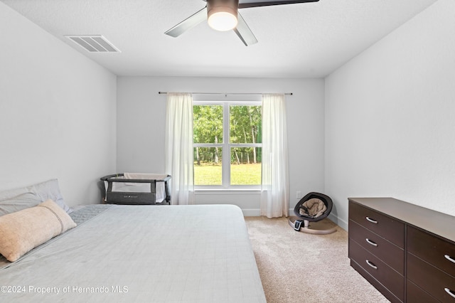 carpeted bedroom featuring ceiling fan and a textured ceiling