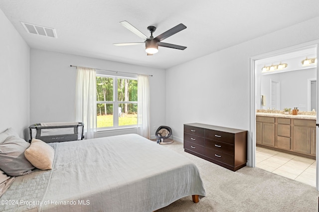 bedroom with connected bathroom, light carpet, and ceiling fan