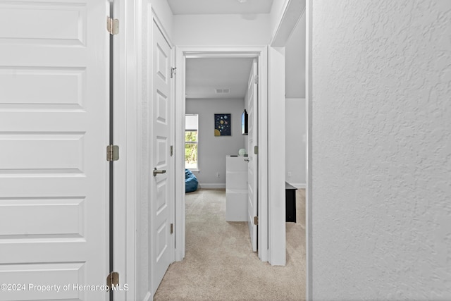 hallway featuring light colored carpet