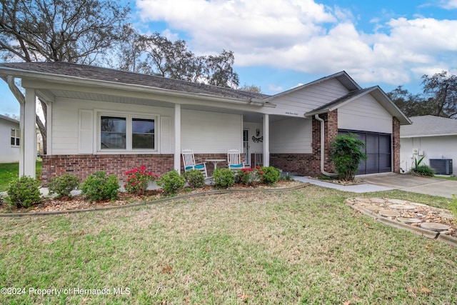 ranch-style home with a garage, cooling unit, and a front lawn