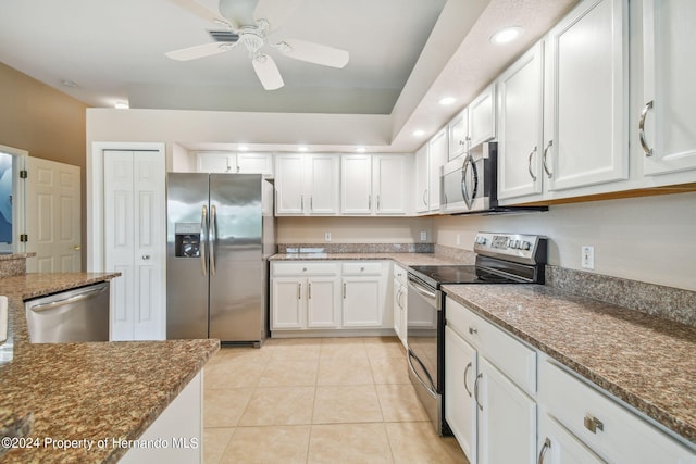 kitchen featuring appliances with stainless steel finishes, dark stone counters, ceiling fan, light tile patterned floors, and white cabinets