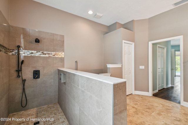 bathroom with wood-type flooring and a tile shower