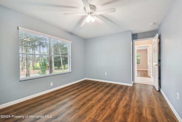 empty room with ceiling fan, a textured ceiling, and dark hardwood / wood-style flooring