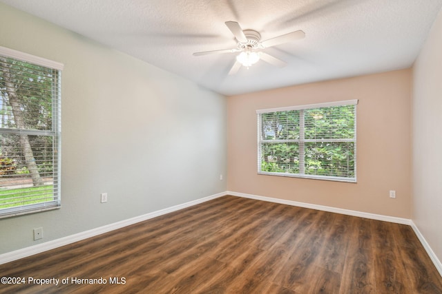 spare room with dark wood-type flooring, ceiling fan, a healthy amount of sunlight, and a textured ceiling