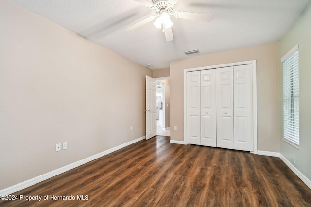 unfurnished bedroom with a textured ceiling, ceiling fan, dark hardwood / wood-style floors, and a closet