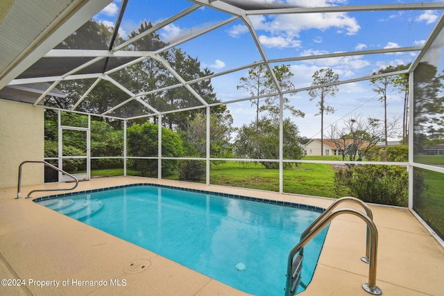 view of pool featuring a lawn, glass enclosure, and a patio area