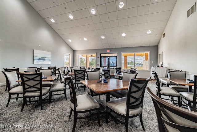 carpeted dining space featuring high vaulted ceiling