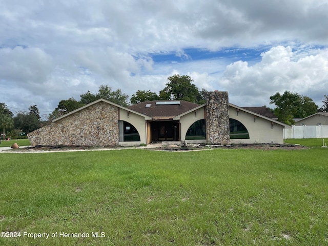 ranch-style home with solar panels and a front lawn