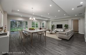 dining room with dark wood-type flooring, a tray ceiling, and a chandelier