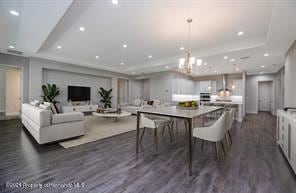 dining space with dark wood-type flooring, a tray ceiling, and a notable chandelier