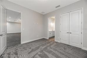 unfurnished bedroom with dark carpet and a closet