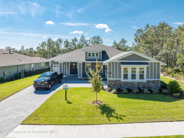 view of front of property with a garage, cooling unit, and a front lawn