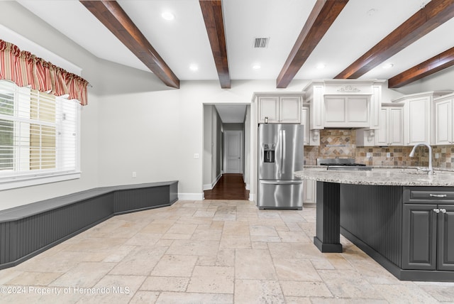 kitchen featuring white cabinetry, backsplash, stainless steel fridge with ice dispenser, light stone countertops, and beamed ceiling