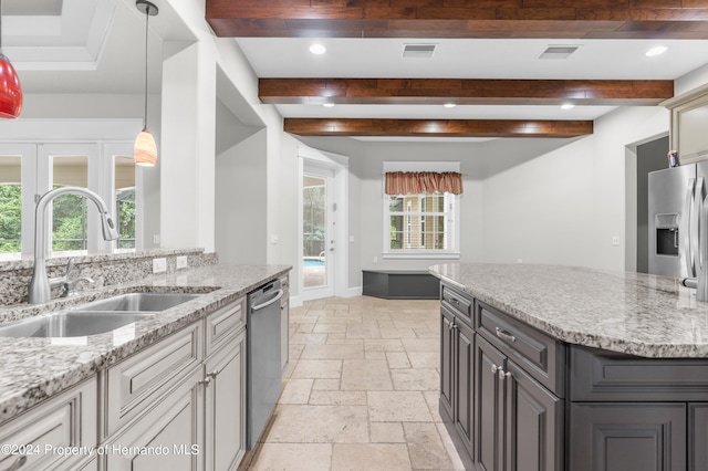 kitchen featuring appliances with stainless steel finishes, beamed ceiling, sink, and light stone countertops