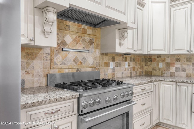 kitchen featuring backsplash, ventilation hood, white cabinets, and high end stainless steel range oven