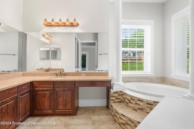 bathroom with vanity, tile patterned flooring, ornate columns, and tiled tub