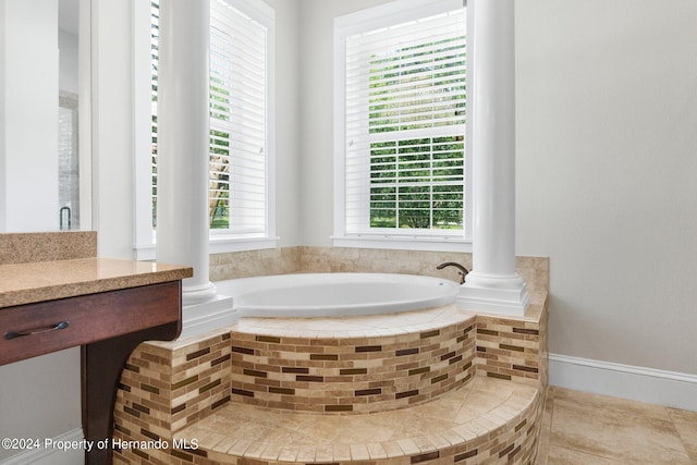 bathroom featuring a relaxing tiled tub, vanity, and tile patterned floors