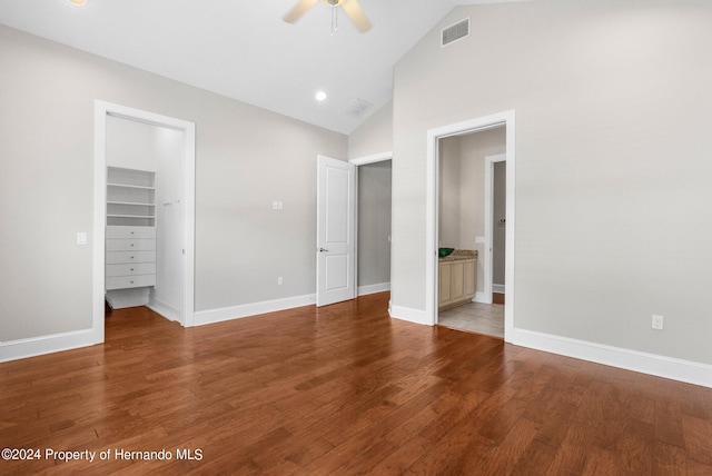 unfurnished bedroom featuring ceiling fan, wood-type flooring, a walk in closet, connected bathroom, and vaulted ceiling